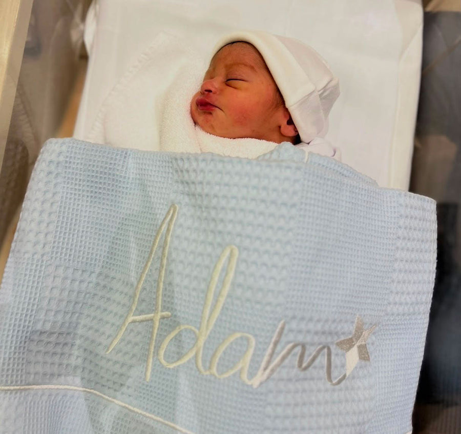 Newborn Adam wrapped in a monogrammed blanket
